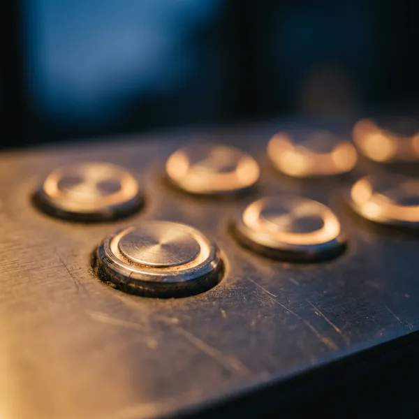 Backlit gate keypad glowing amber at night in shallow focus with blank unmarked keys