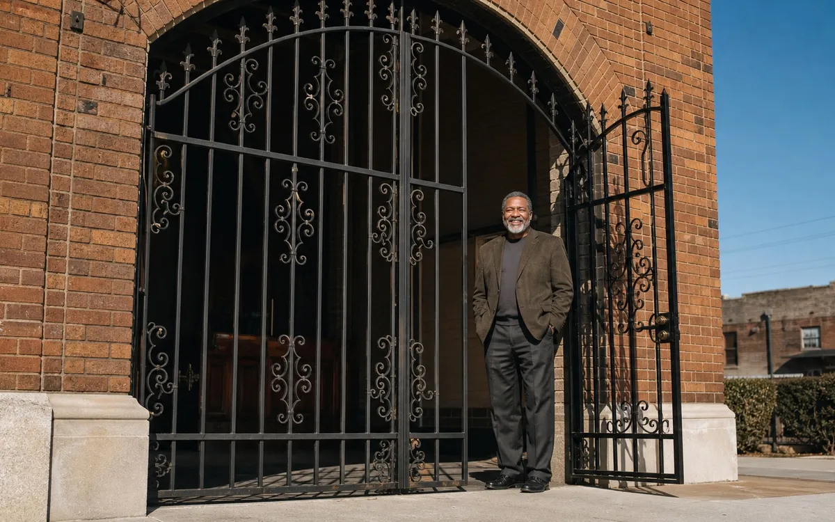 Business owner standing beside ornamental iron security gates at a Detroit commercial building entrance in daylight